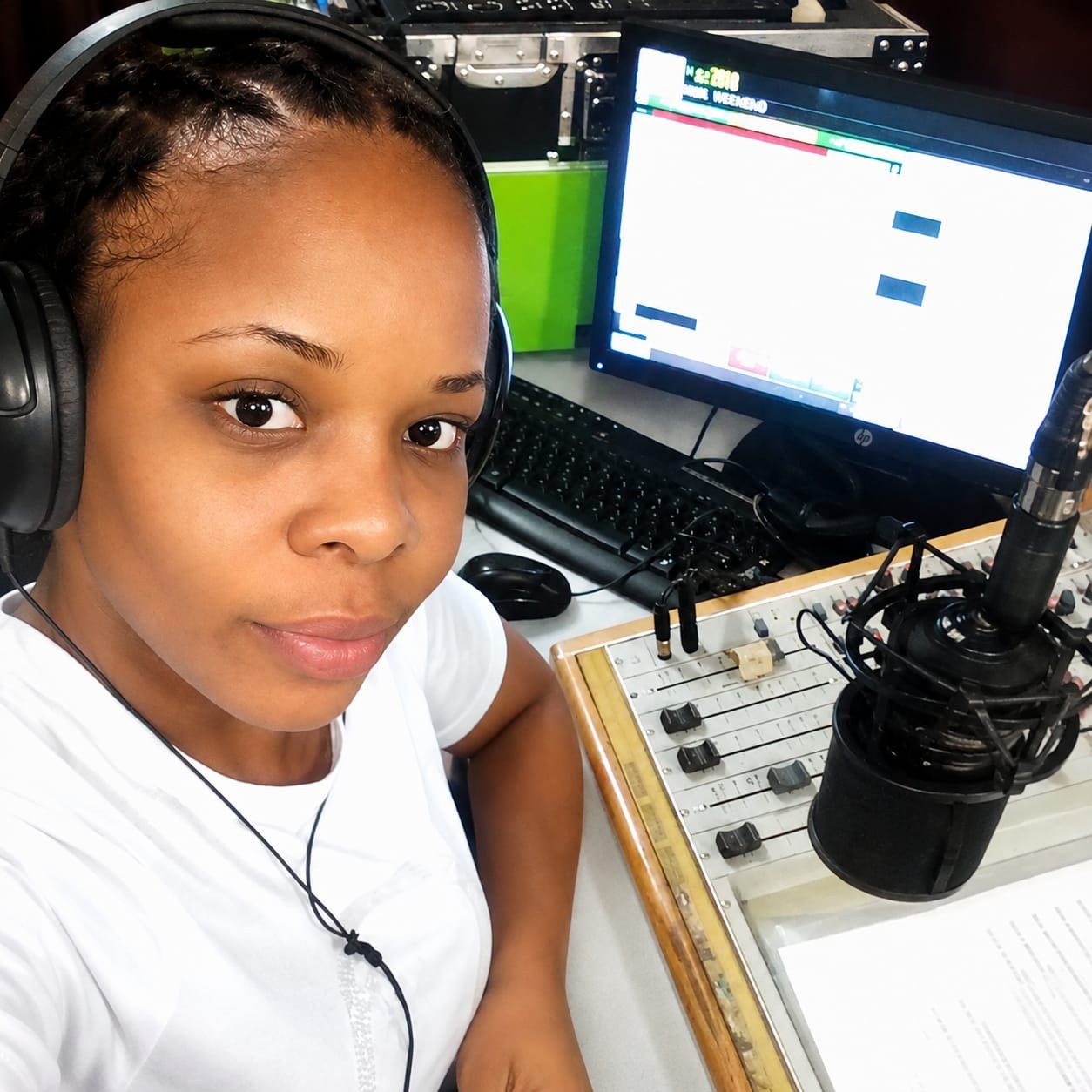 Grace Amarachi Ihesiulo at a radio broadcast desk, wearing headphones beside a studio mixing console
